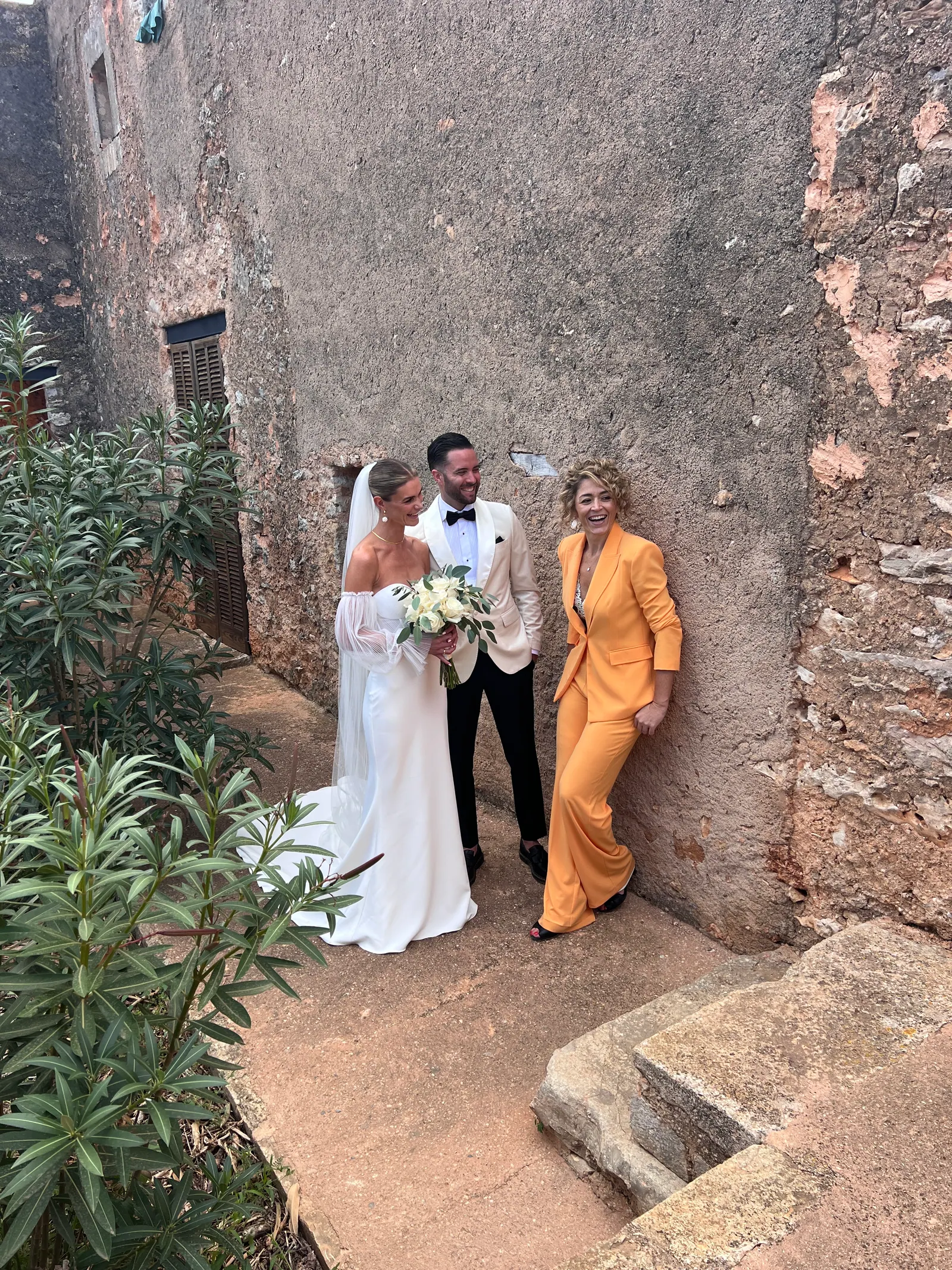 A couple and Ximena sharing a quiet moment beside an old stone wall