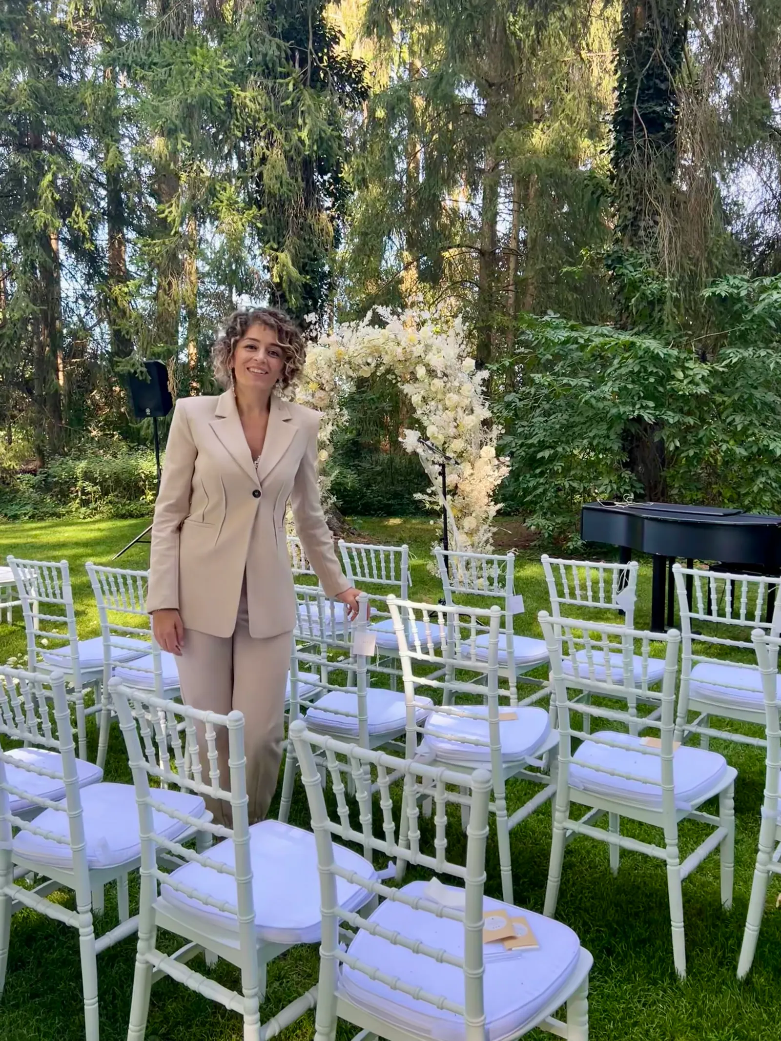 Ximena smiling among white chairs and flowers prepared for an outdoor ceremony