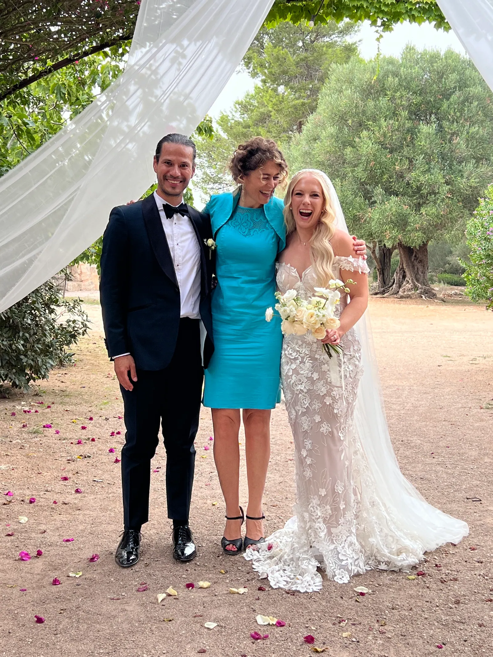 Ximena and a couple laughing together beneath white drapery and trees