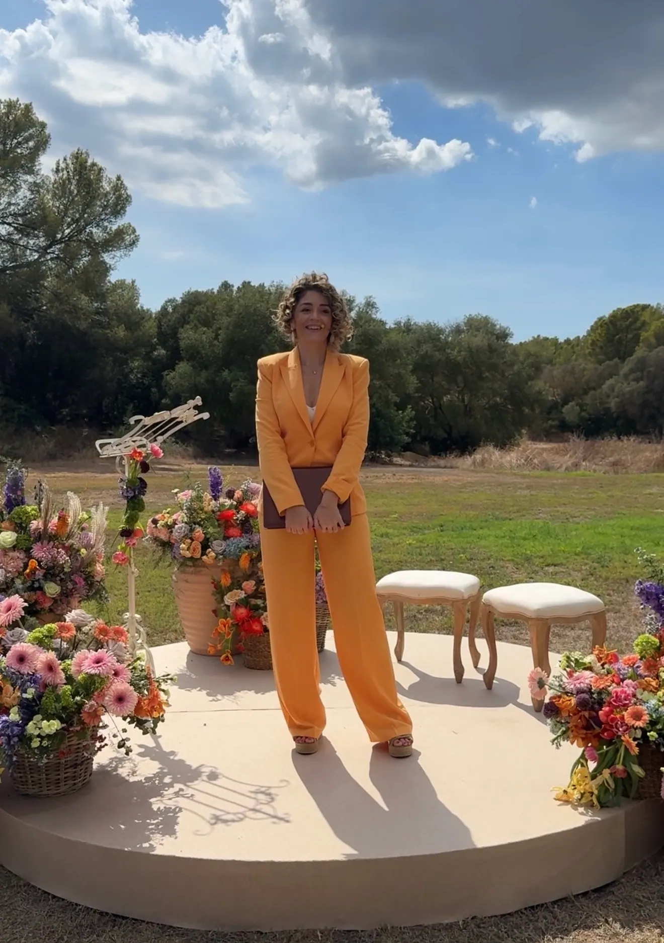 Ximena holding her ceremony book beside flowers in an outdoor ceremony setting