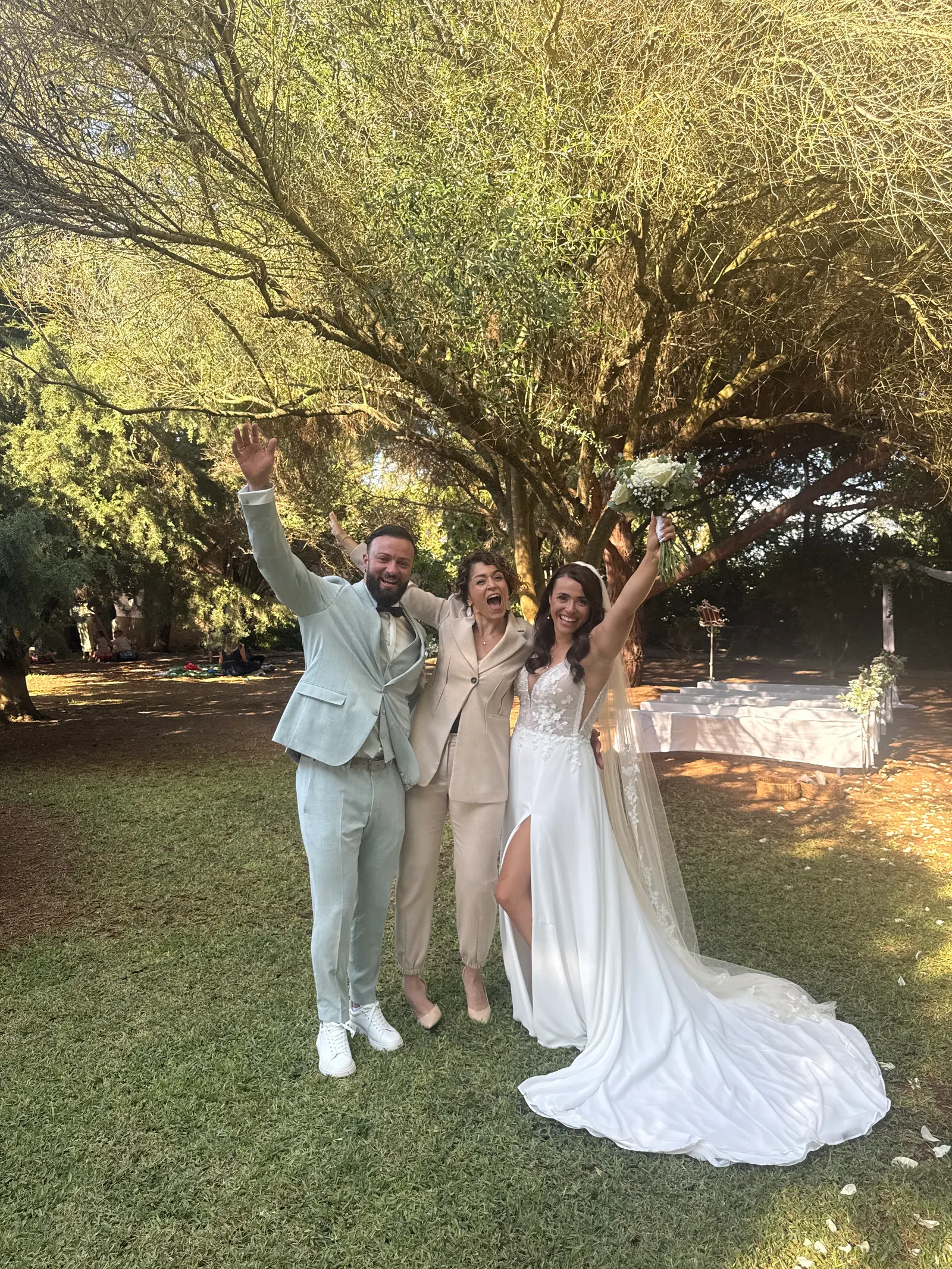 A couple and Ximena celebrating beneath trees after their ceremony